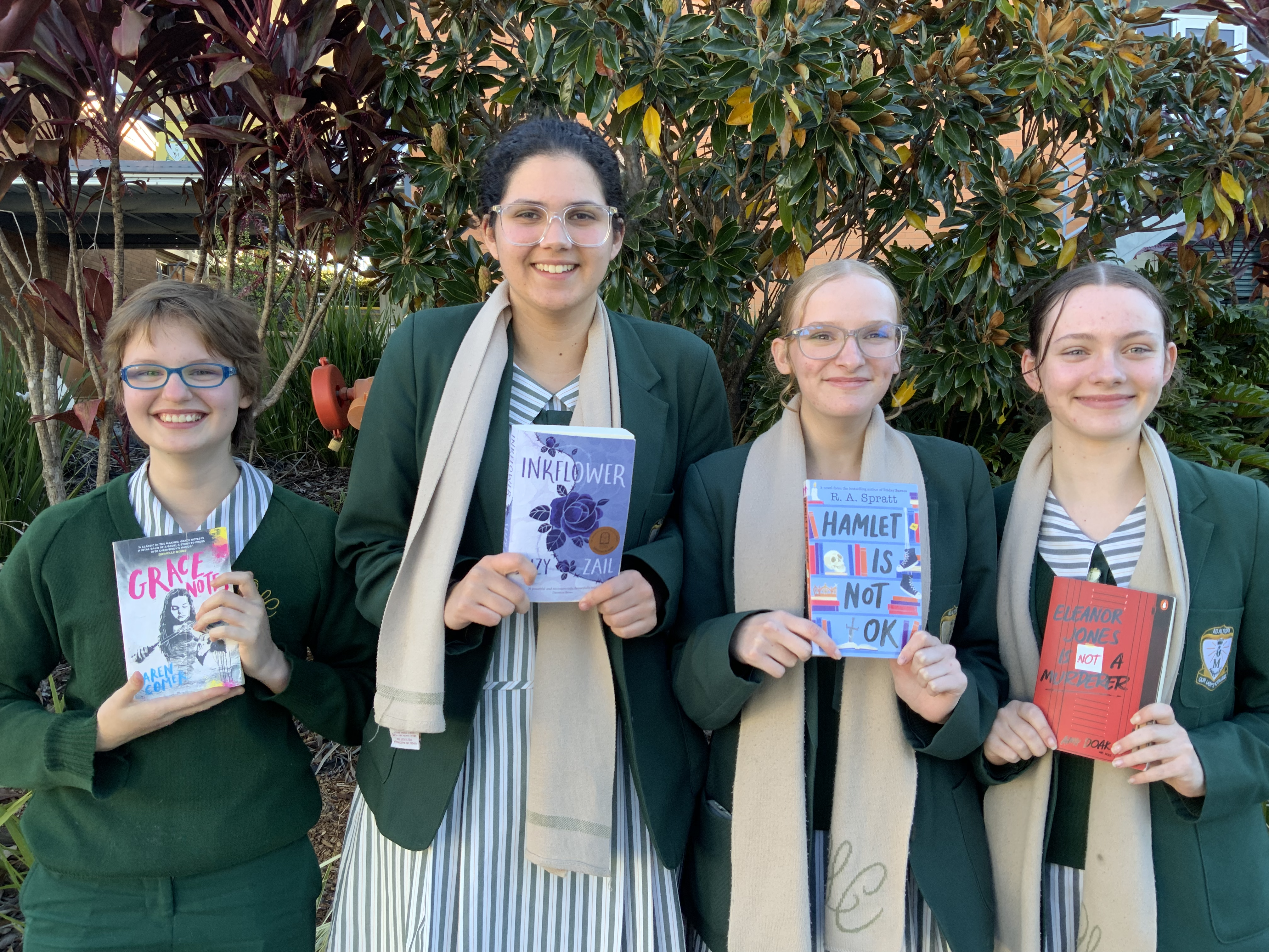 four students holding up books