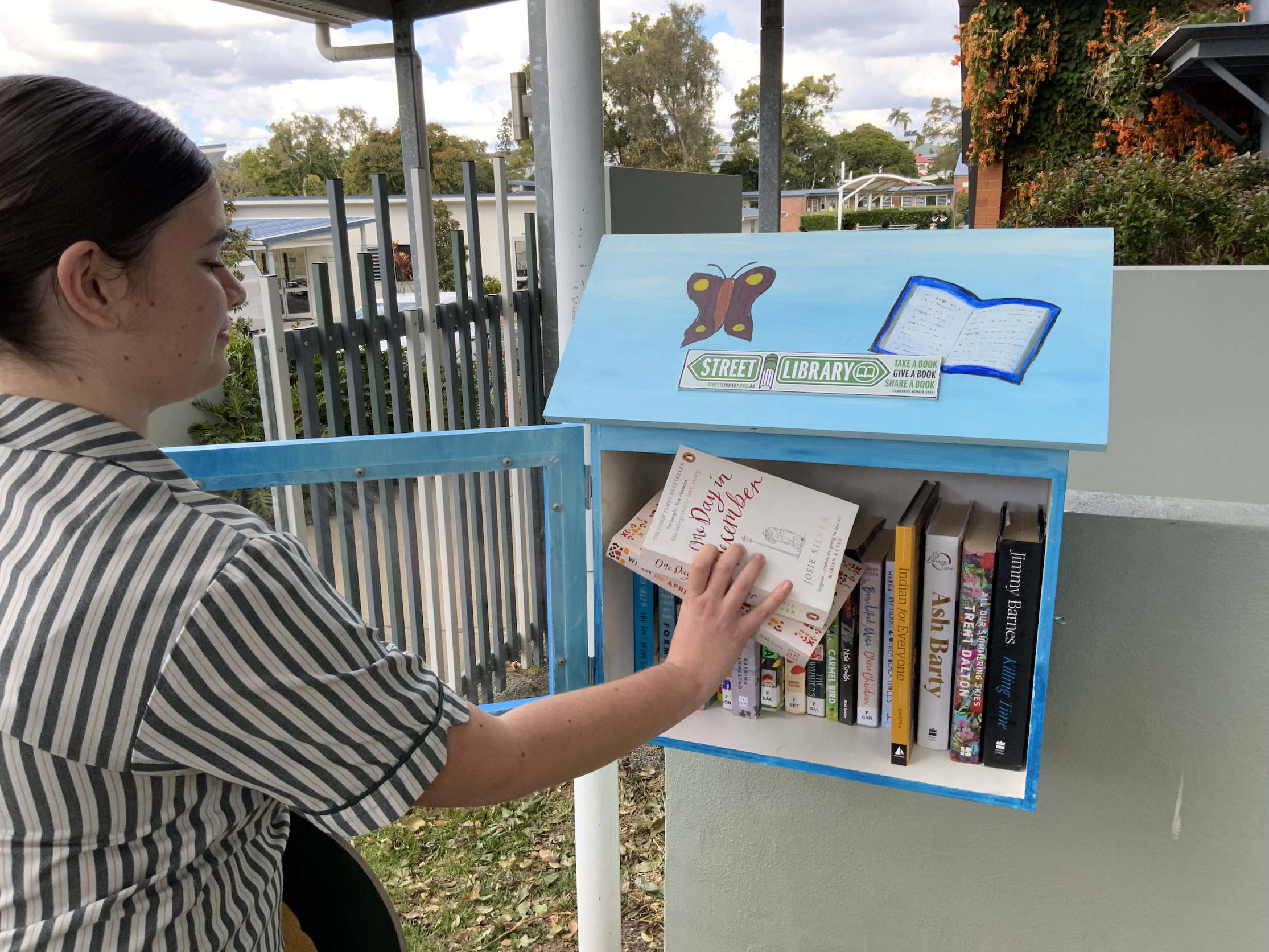 student replacing a book in the community library box